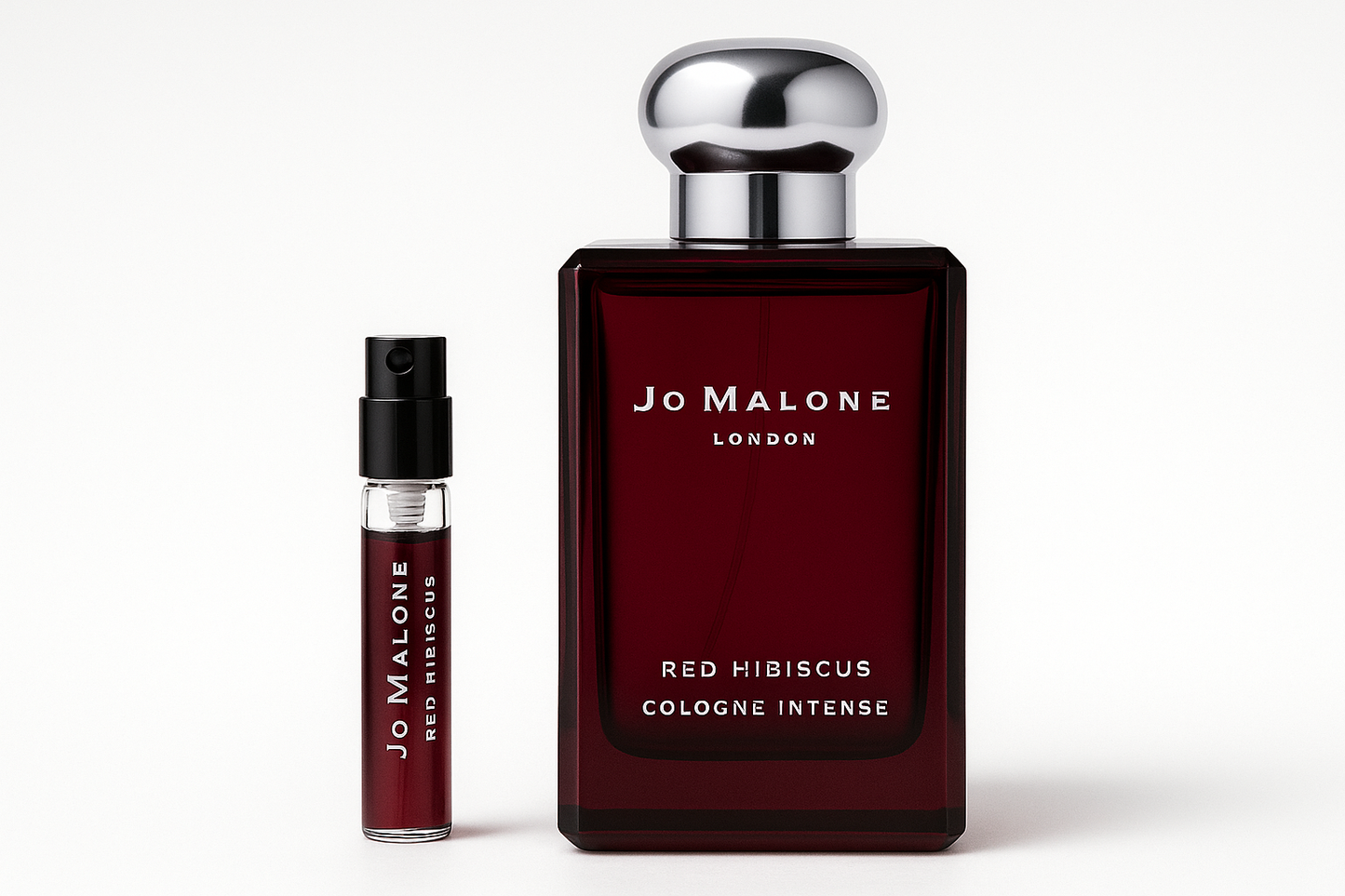 Jo Malone 红木槿古龙水 2ml 样品放在 Jo Malone 红木槿古龙水 100ml 香水瓶旁边,深红色瓶身上有白色字样