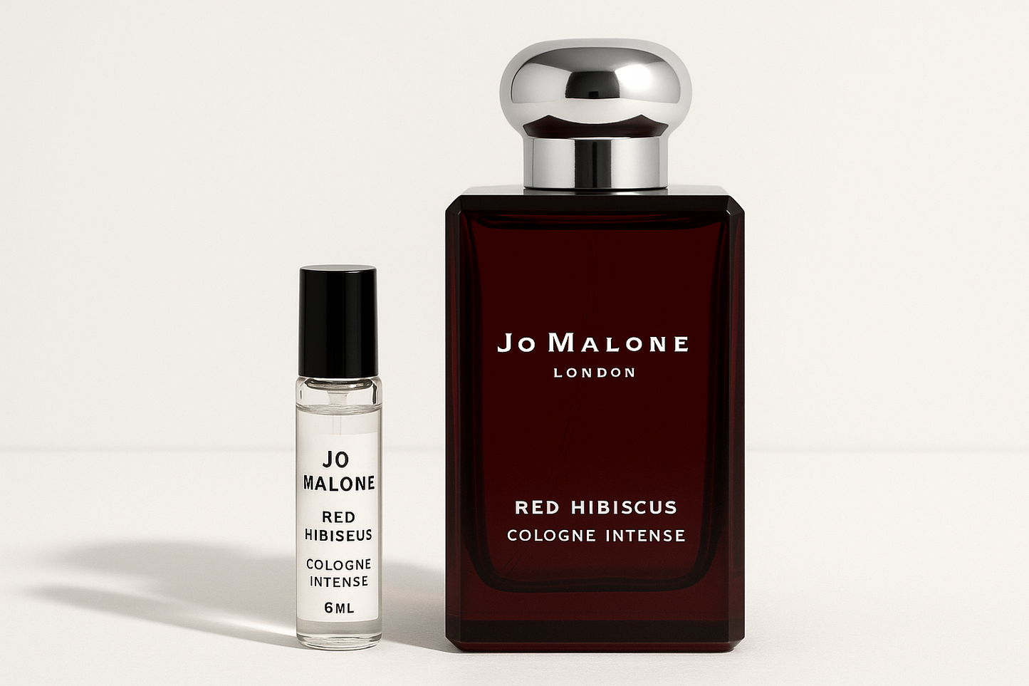 Jo Malone 红木槿古龙水 6ml 样品放在 Jo Malone 红木槿古龙水 100ml 香水瓶旁边,深红色瓶身上有白色字样